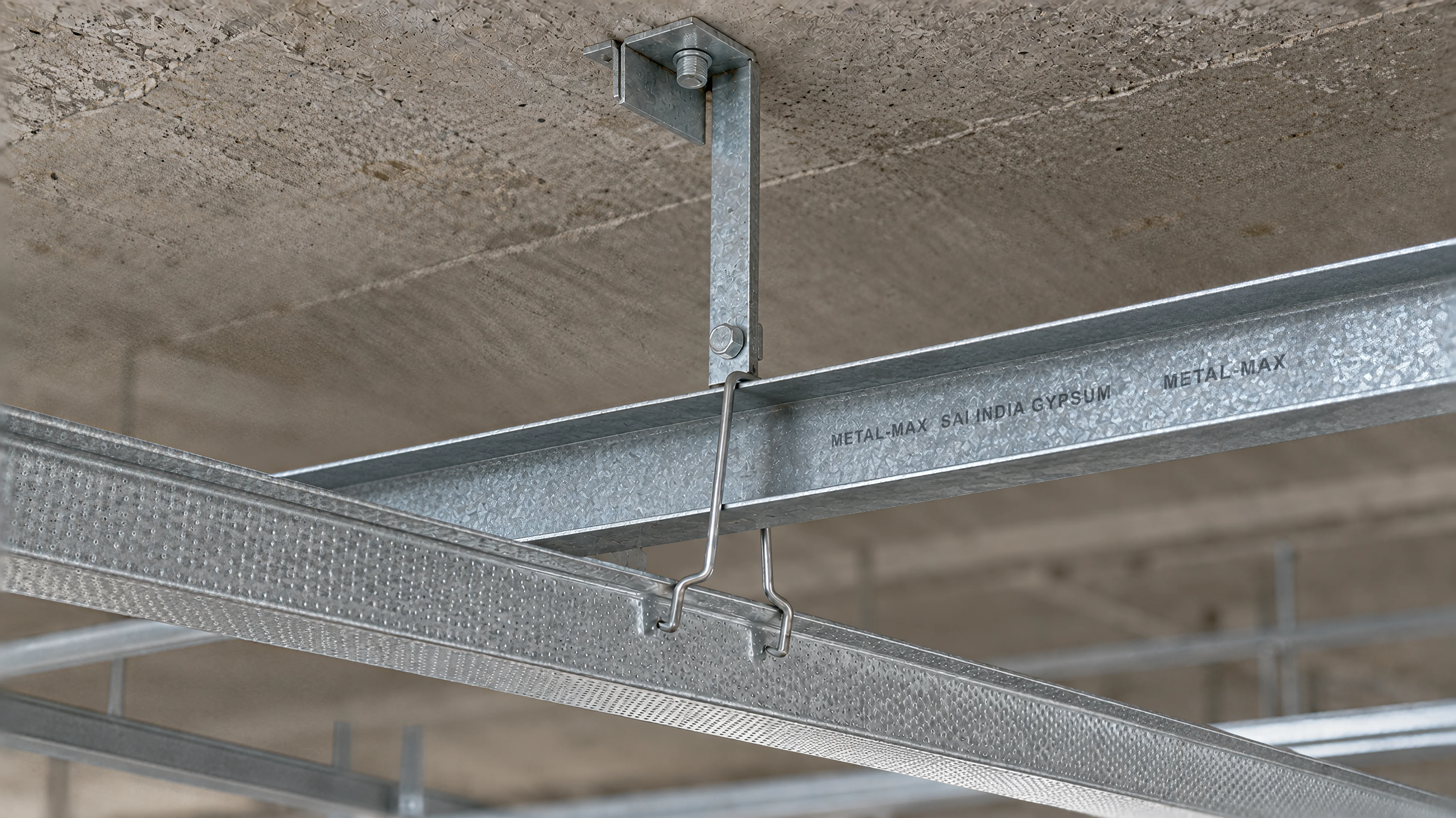 One junction of the ceiling frame: soffit cleat, ceiling angle, intermediate channel, and a ceiling section held below it by a wire clip
